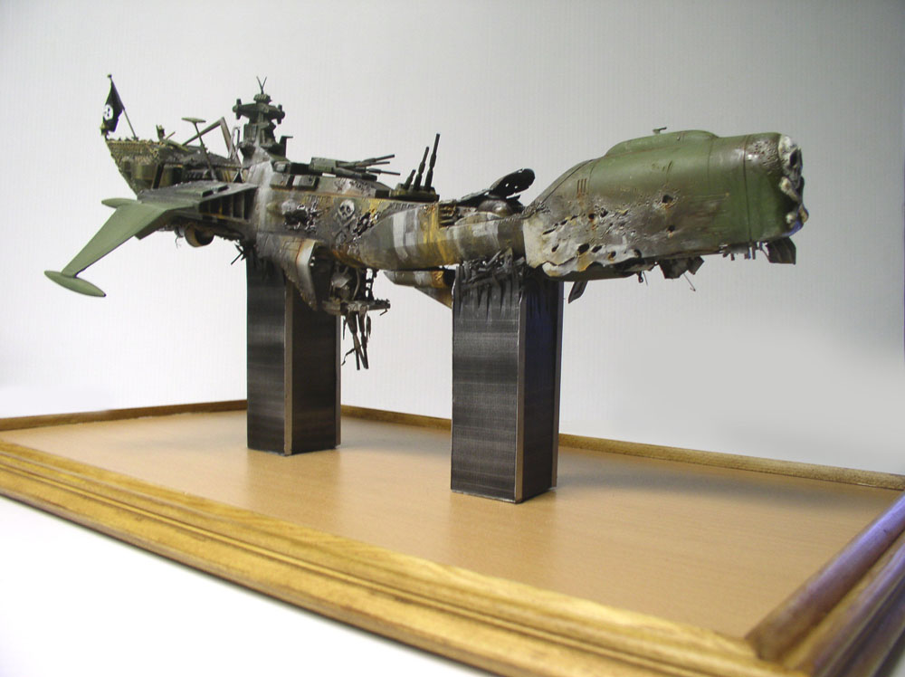 Maquette du vaisseau pirate Arcadia d'Albator endommagé, posée sur socle bois avec supports métalliques