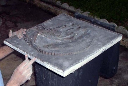 Maquettiste présentant un bas-relief gris sculpté représentant l'Alien, le Huitième Passager