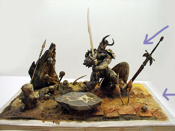 Diorama of a horned warrior brandishing a sword amid skulls and spears, with arrows pointing out details